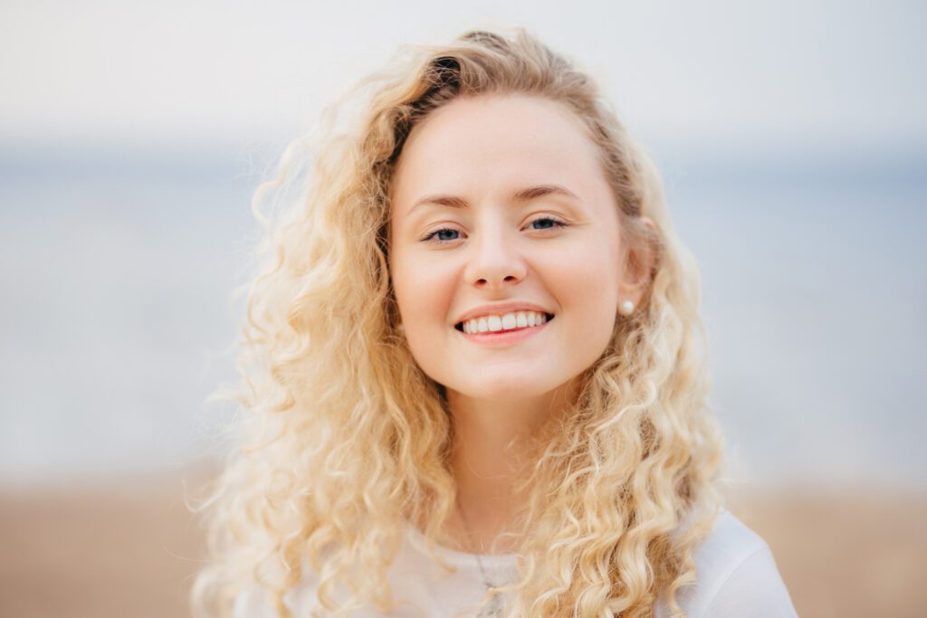 Headshot of beautiful woman with friendly smile, has healthy skin, being in good mood